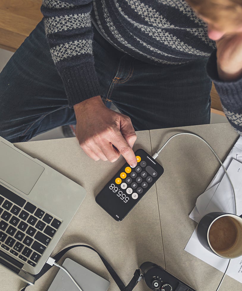 A person using a calculator on their iPhone to calculate cost of deposits